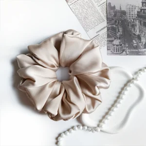 Scrunchie XL z satyny jedwabnej w kolorze beżowym.