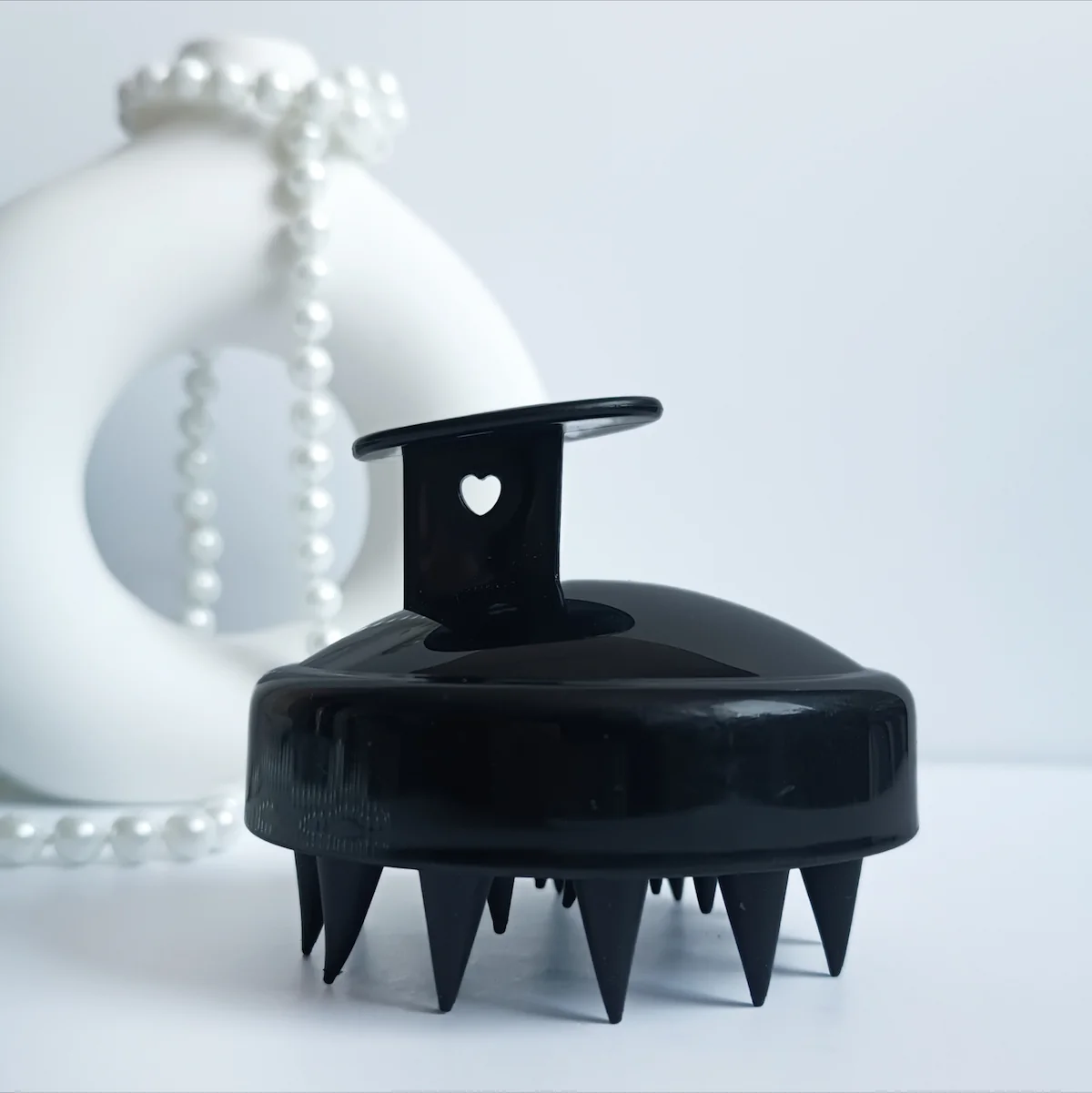 Masażer do skóry głowy w kolorze czarnym.