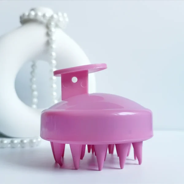 Masażer do skóry głowy w kolorze różowym.