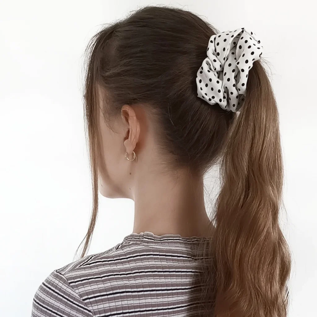 Scrunchie biała w czarne kropki w rozmiarze L, zaprezentowana na włosach.