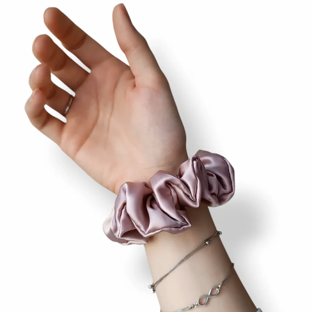 Jedwabna scrunchie w rozmiarze M na nadgarstku.