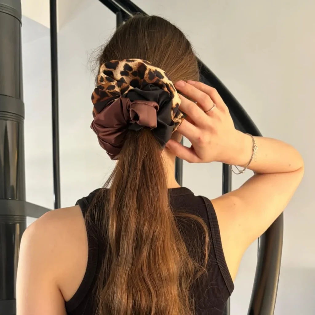 Trzykolorowa scrunchie w rozmiarze XL na włosach.
